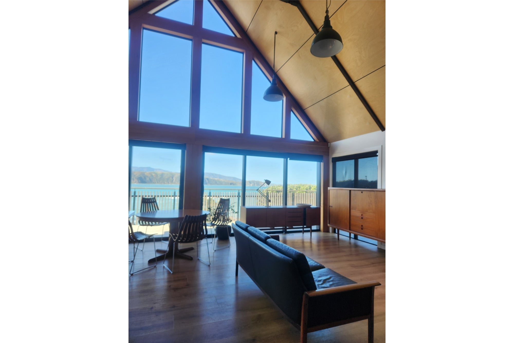 Midcentury house with a frame roof. With midcentury furniture and industrial lighting.