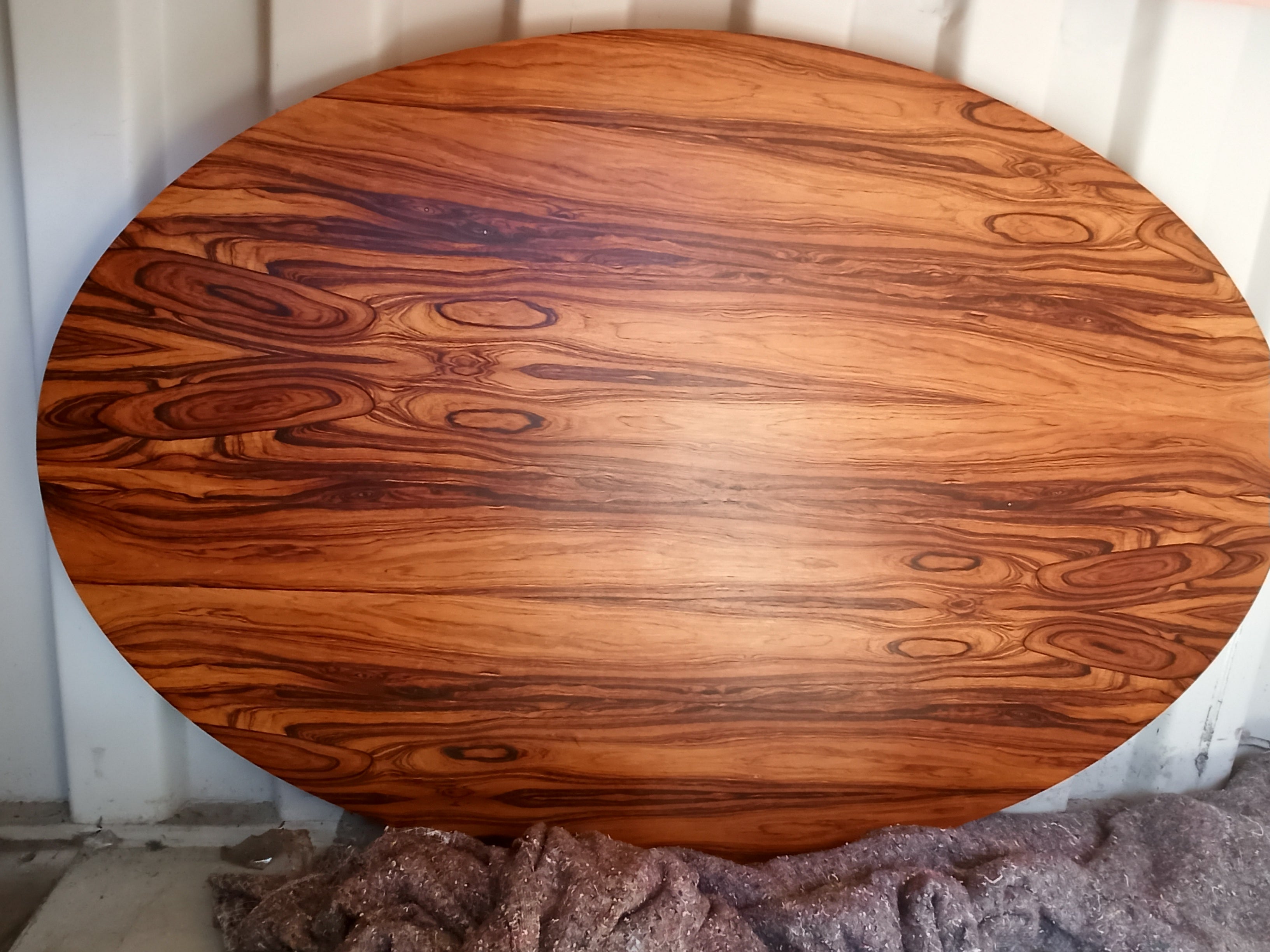 A highly figured Rosewood oval table top on its side in a shipping container.