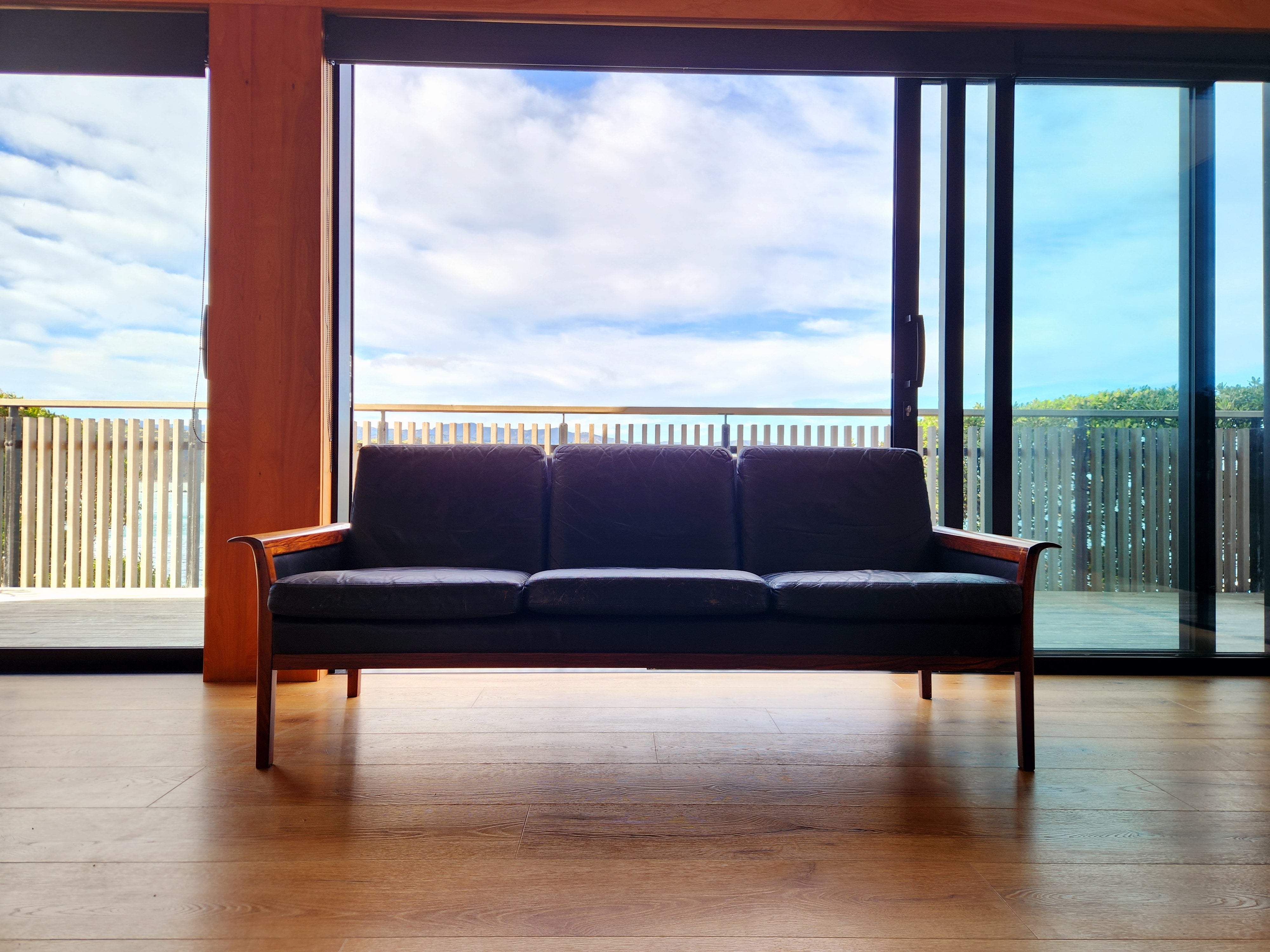 Mid Century Sofa. Viewed from in front with bright backdrop of blue sky and clouds.