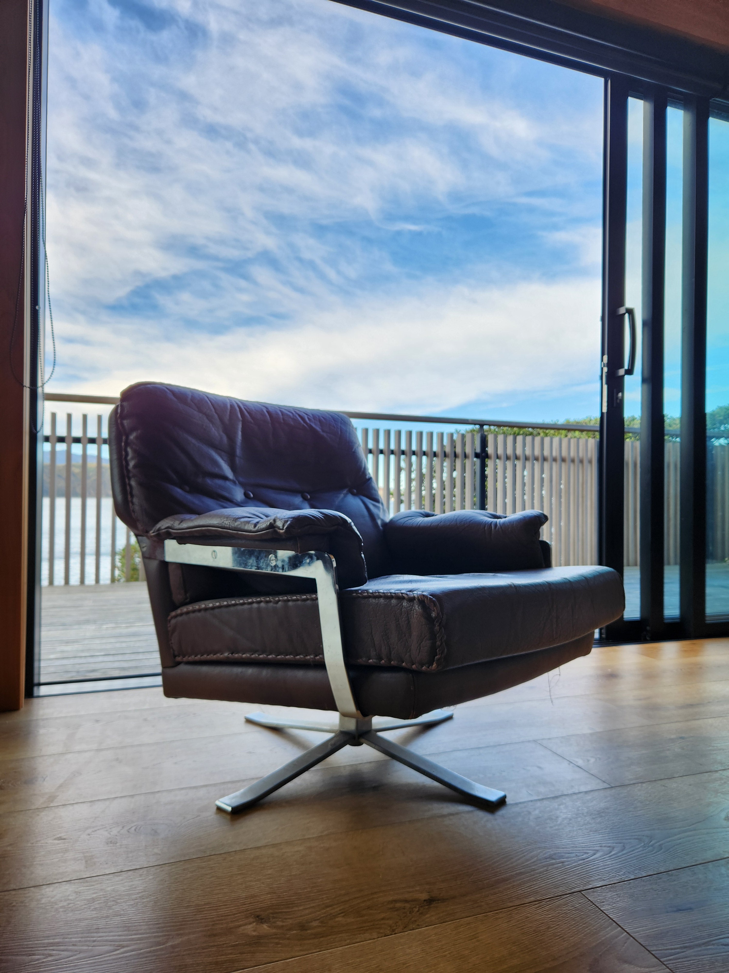 Mid Century Danish Swivel Armchair. With clouds and blue sky behind.