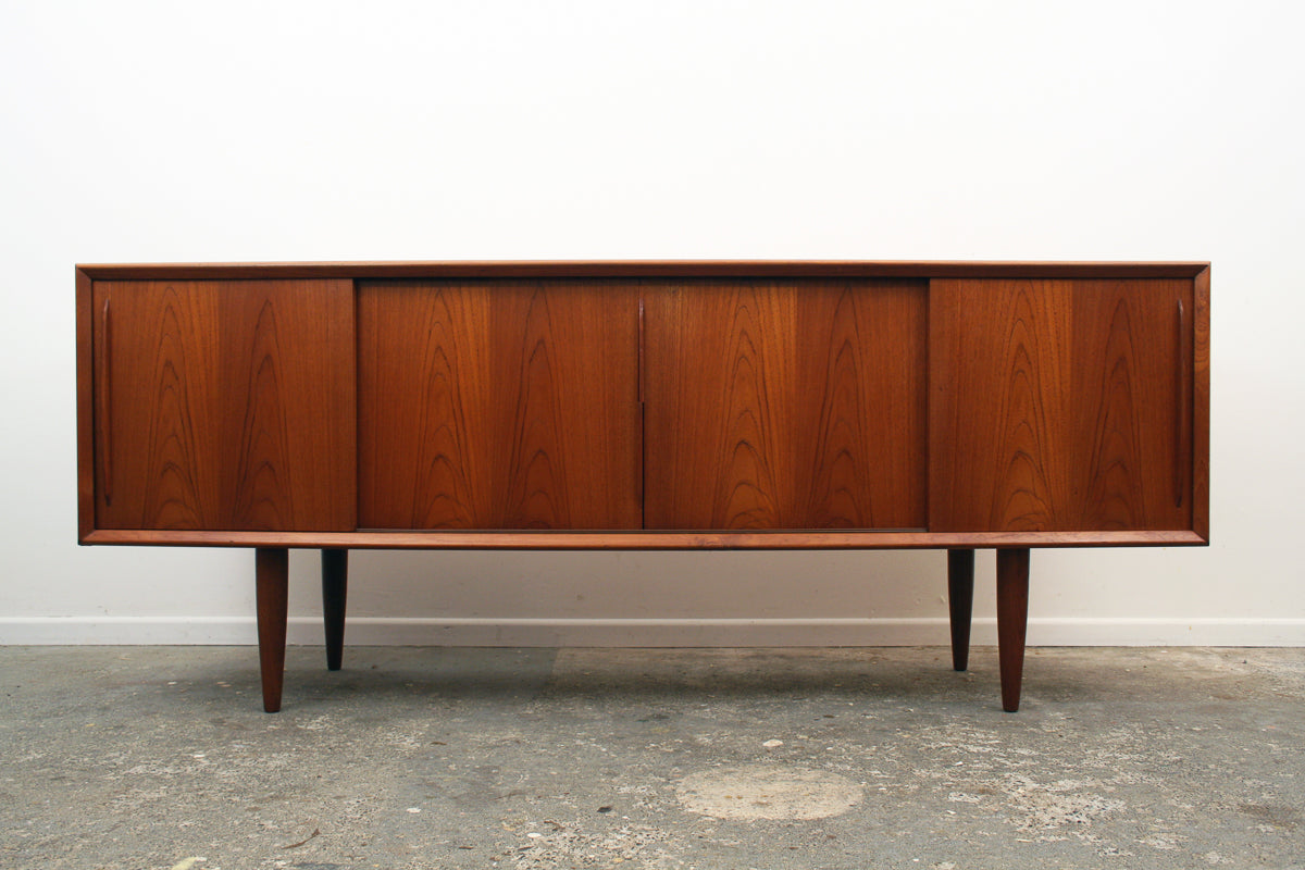 A mid century sideboard by H P Hansen in Teak. Four sliding doors with book matched, highly figured Teak veneer. 