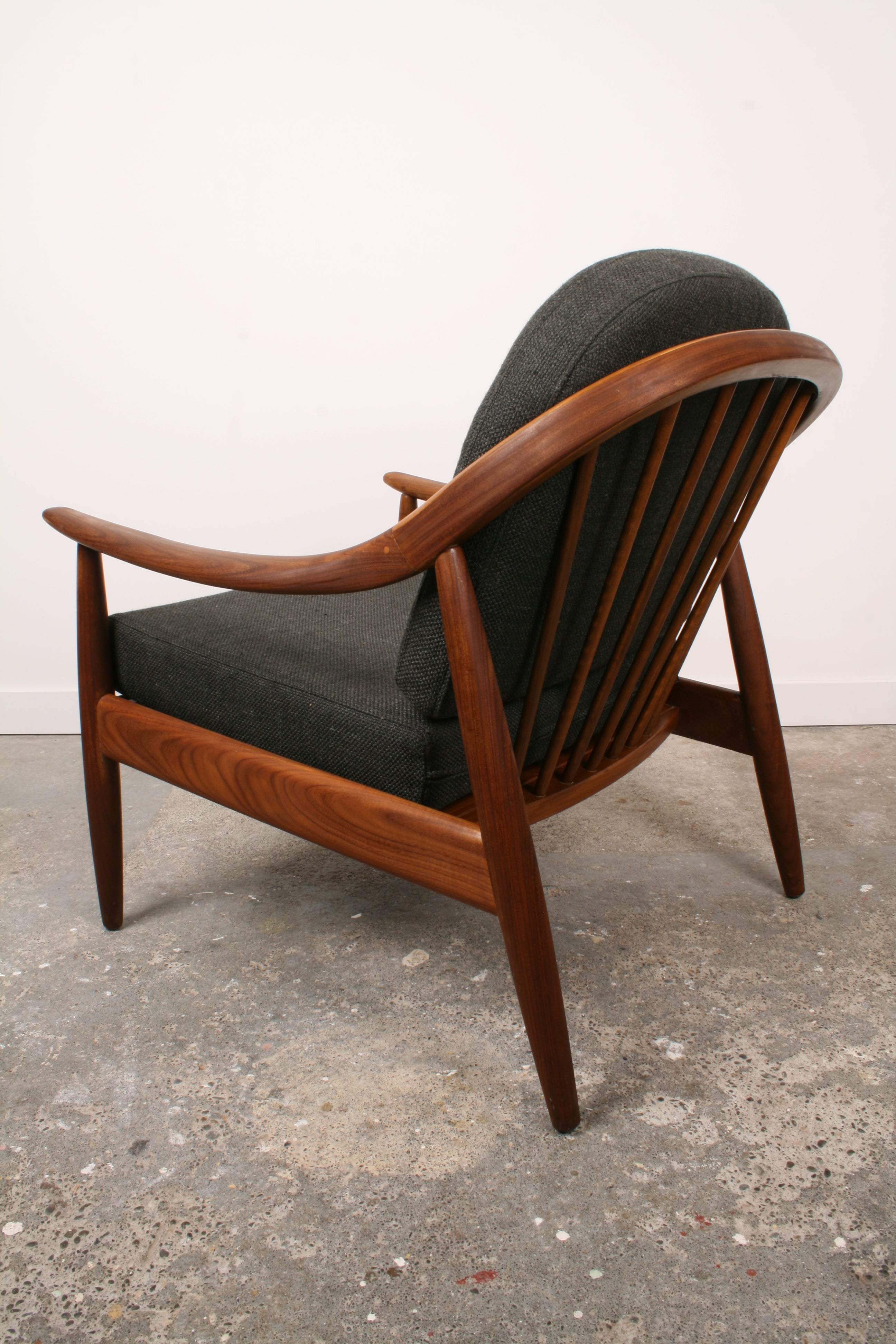 Mid Century Teak armchair from side and rear. Highlighting the curved Teak back and spindles.