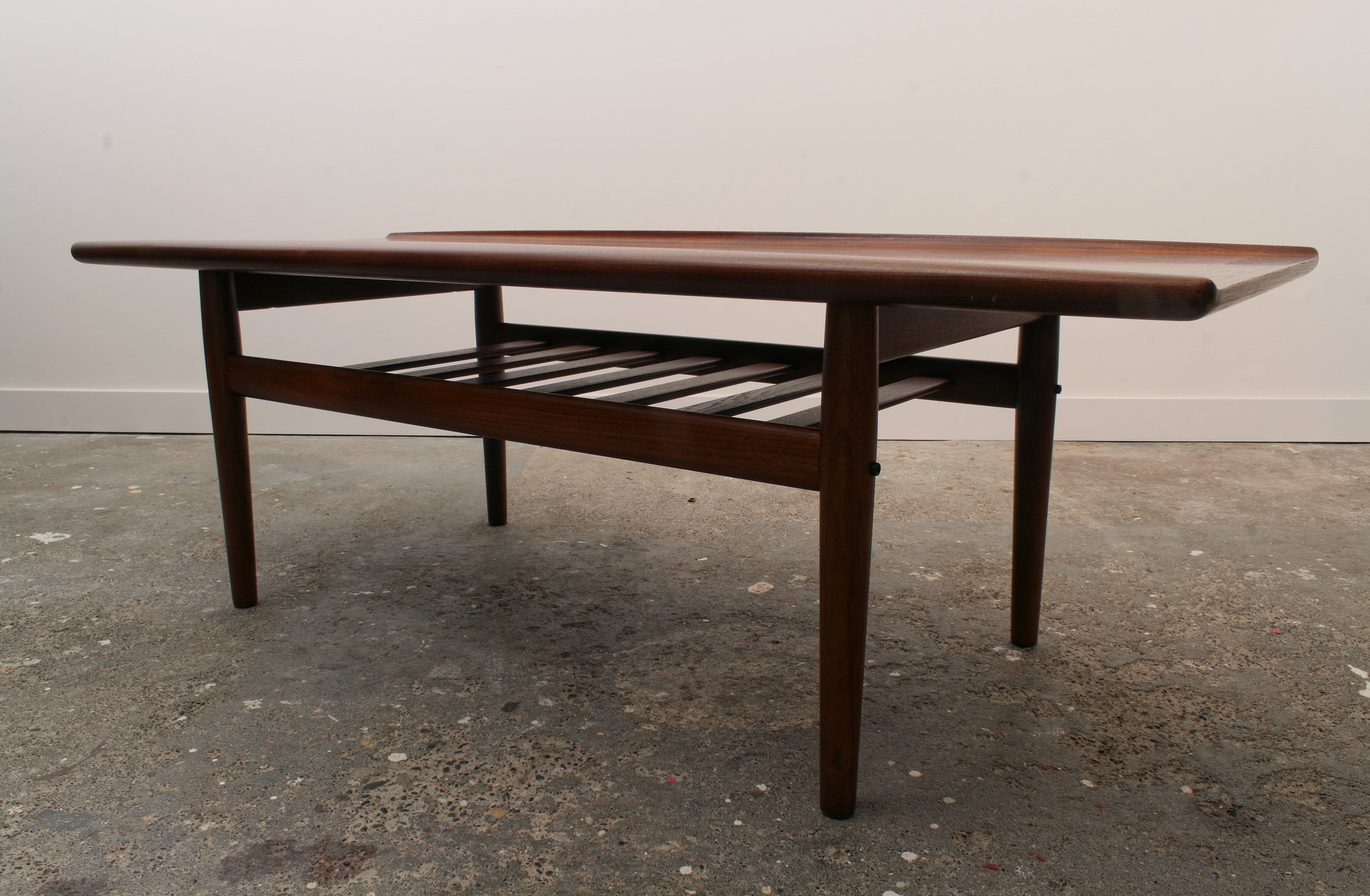 Mid Century Danish Teak Coffee Table. Dark lit side shot highlighting the sleek profile.