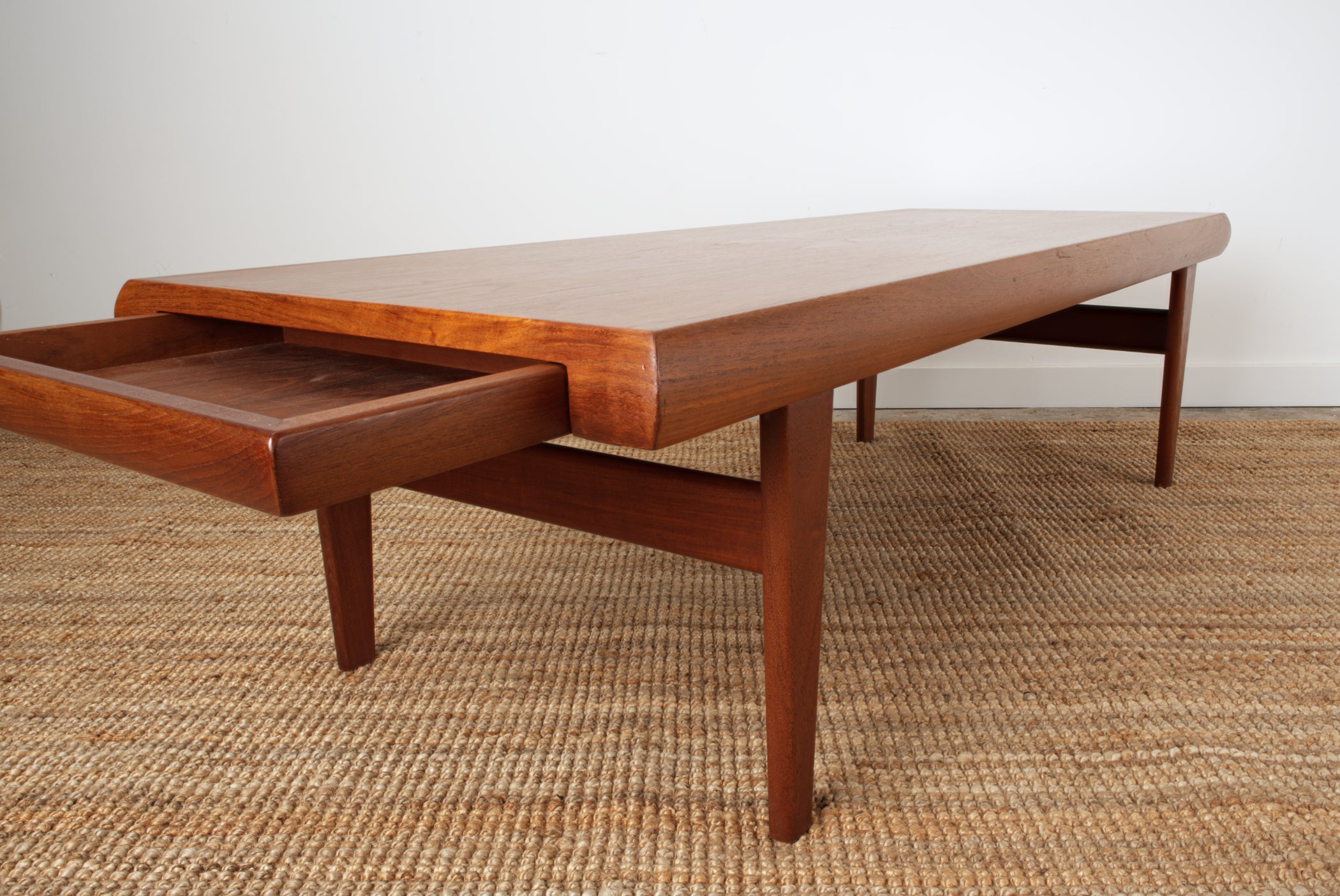 Johannes Andersen designed coffee table in Teak. From end profile with inset drawer open.