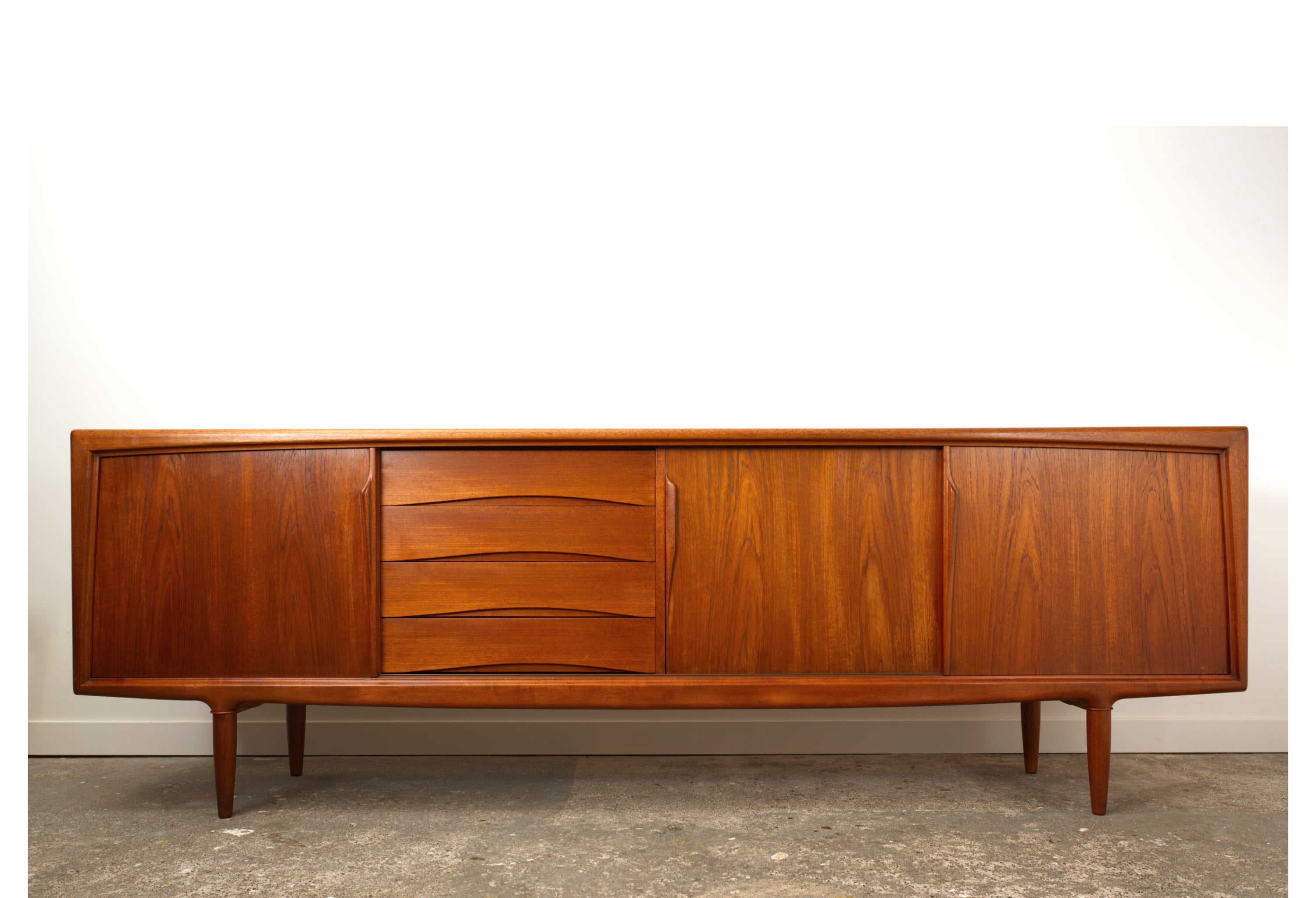 Teak Danish sideboard by Gunni Omann. With three sliding doors. With sculpted details to thehandles, drawers, legs and frame.
