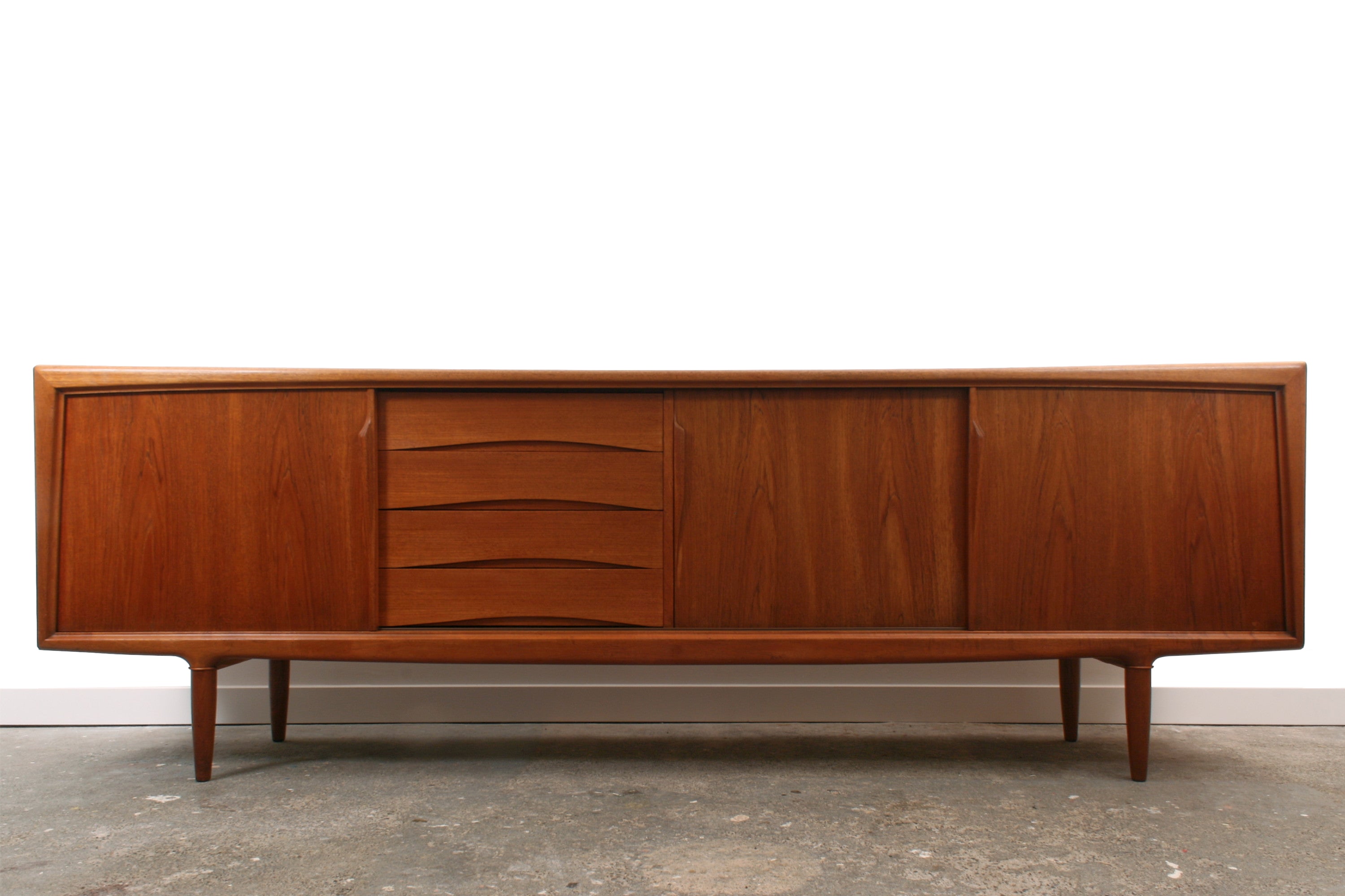 Teak Danish sideboard by Gunni Omann. With three sliding doors. With sculpted details to thehandles, drawers, legs and frame.