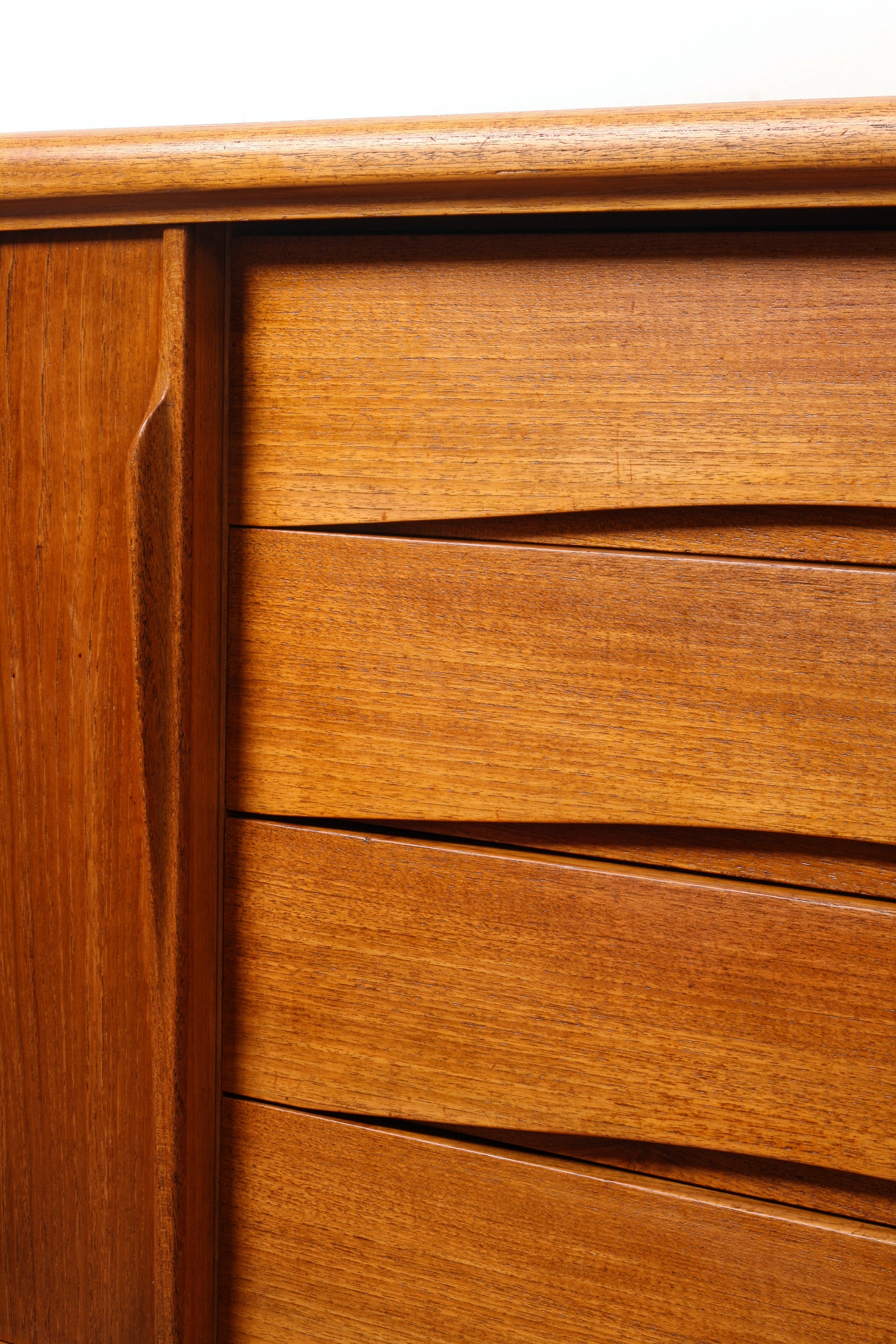 Danish teak sideboard showing sculpted handle and curved drawer pulls.