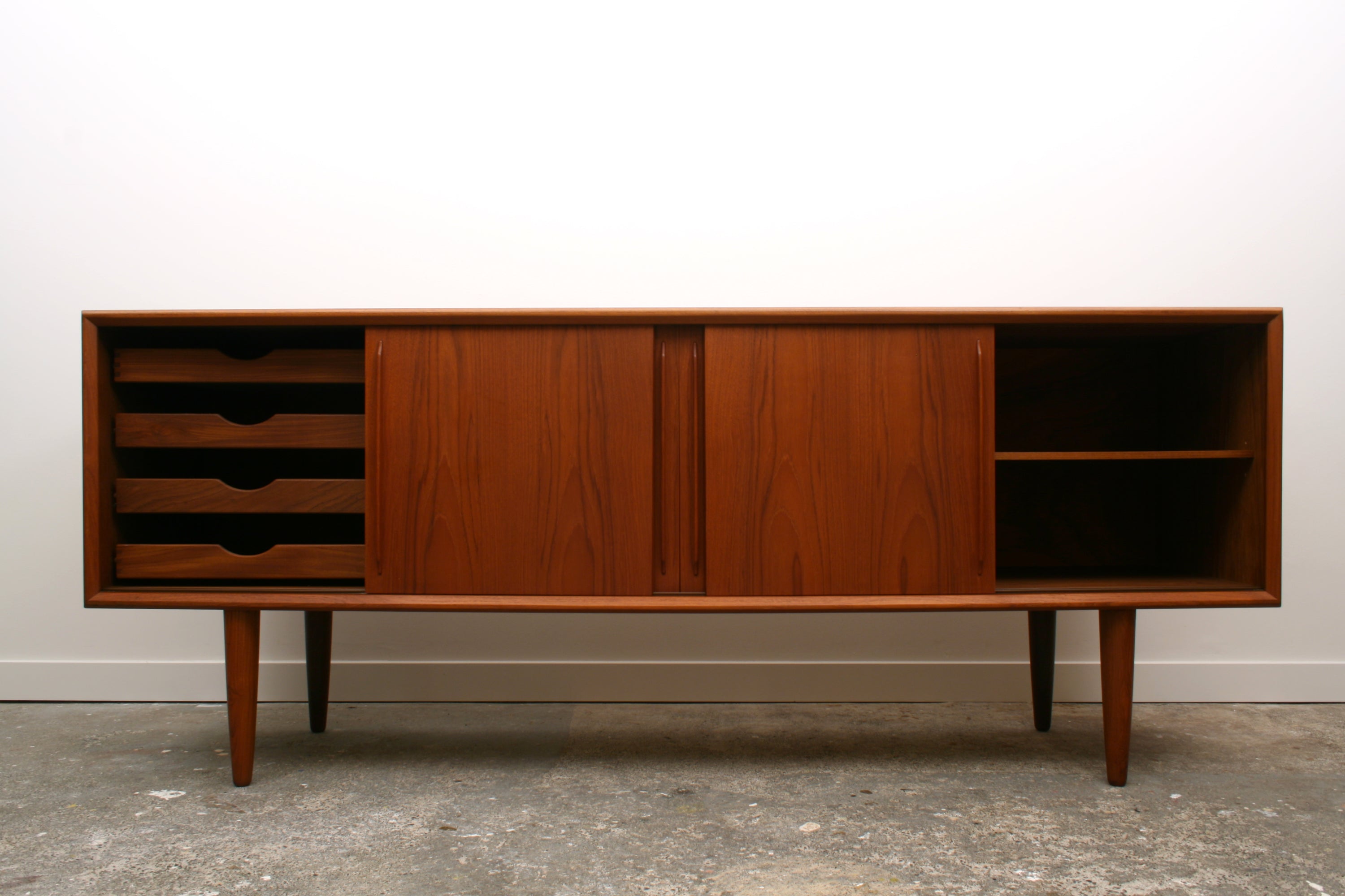 Danish Teak Mid Century Sideboard by H P Hansen. End doors slid open revealing a left cmpartment with three drawers and a right compartment with an adjustable shelf.
