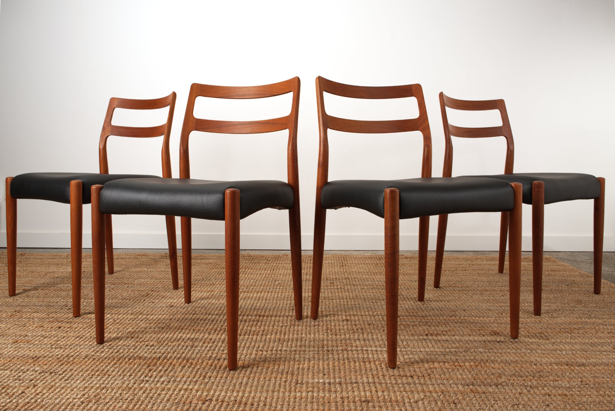 Four Johannes Andersen 'Anne' chairs showing off the the sculpted curves of the back rest rails.