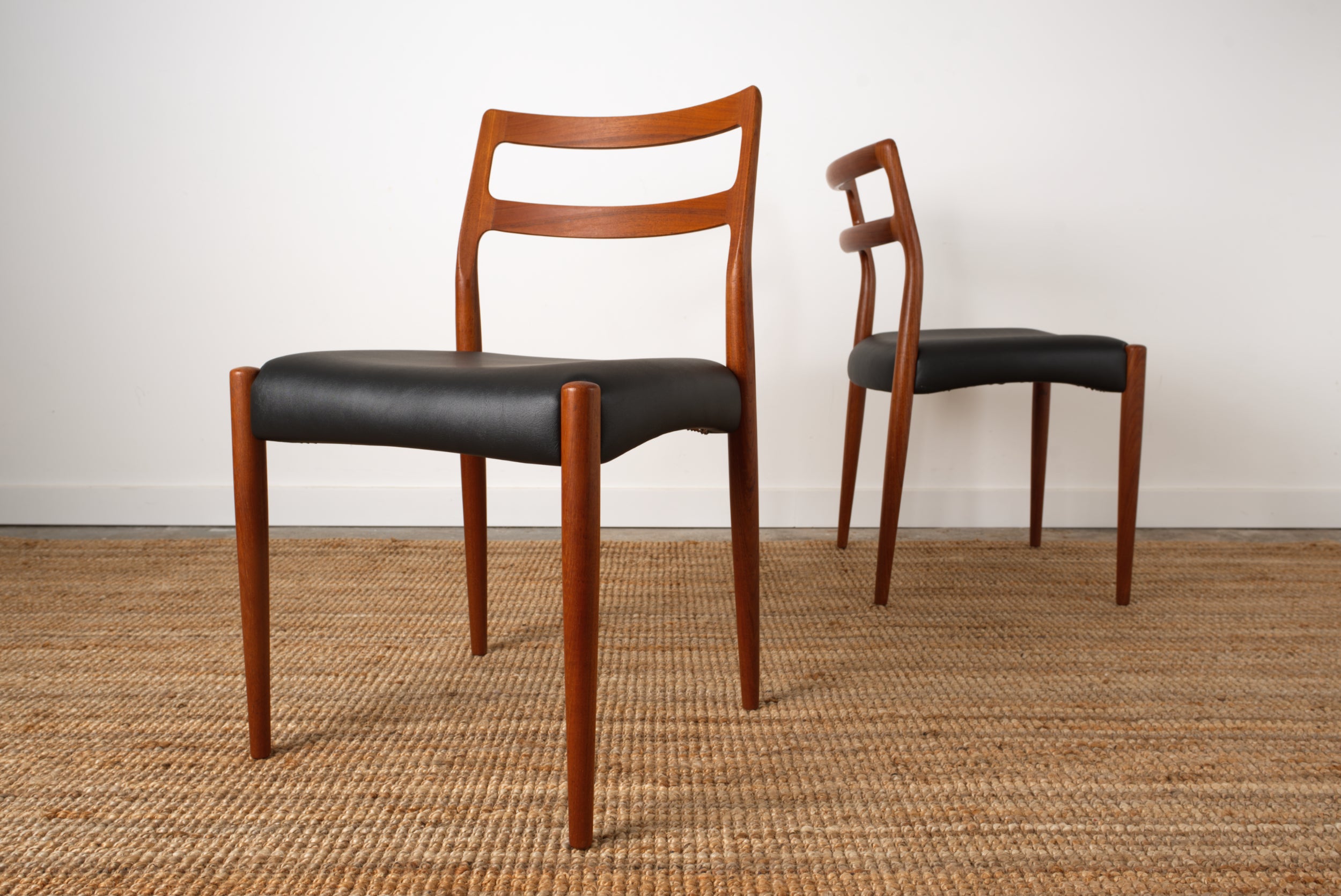 A pair if Johannes Andersen 'Anne' chairs showing off the the sculpted curves of the back rest rails.
