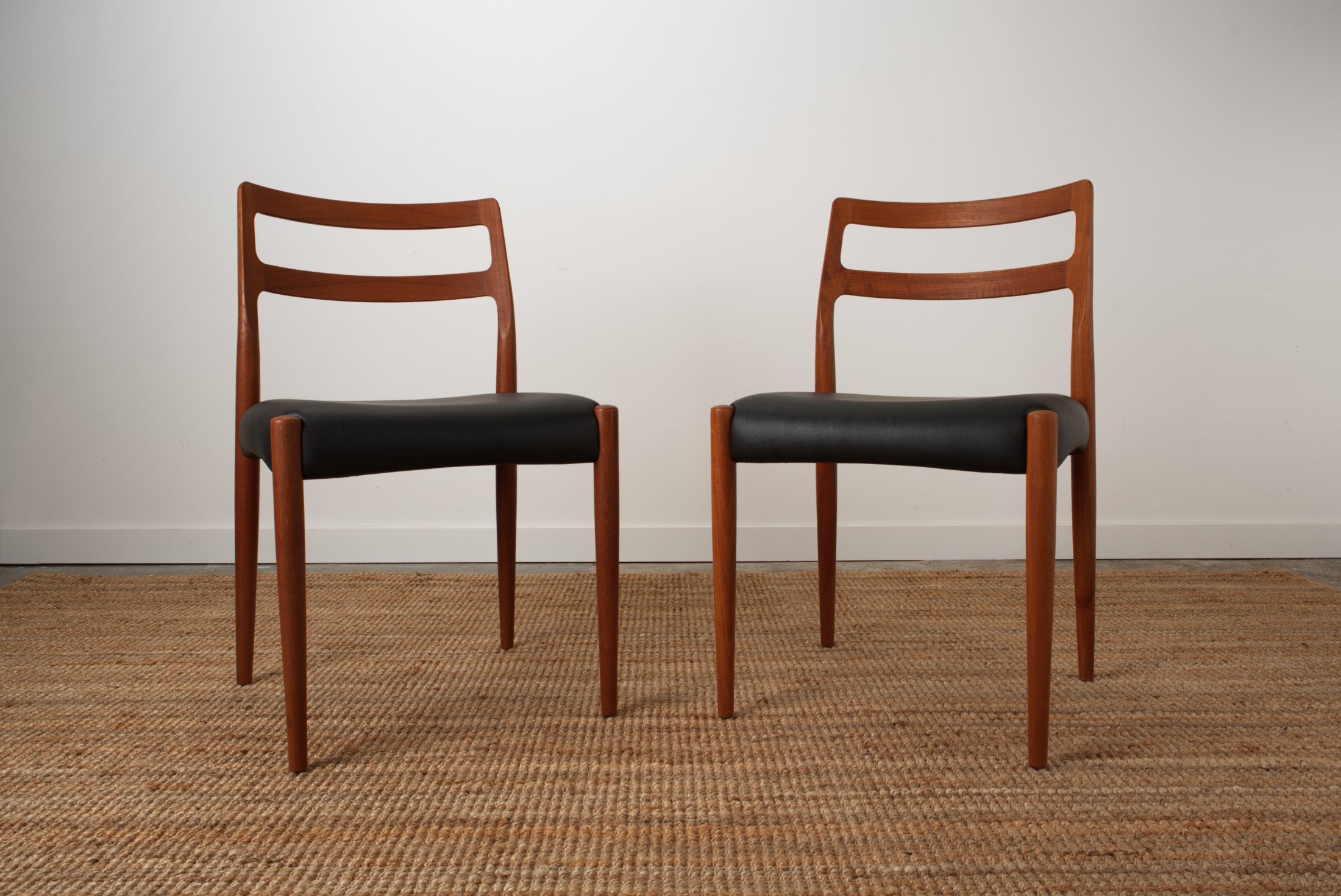 A pair if Johannes Andersen Danish chairs showing off the the sculpted curves of the back rest rails. From the front.