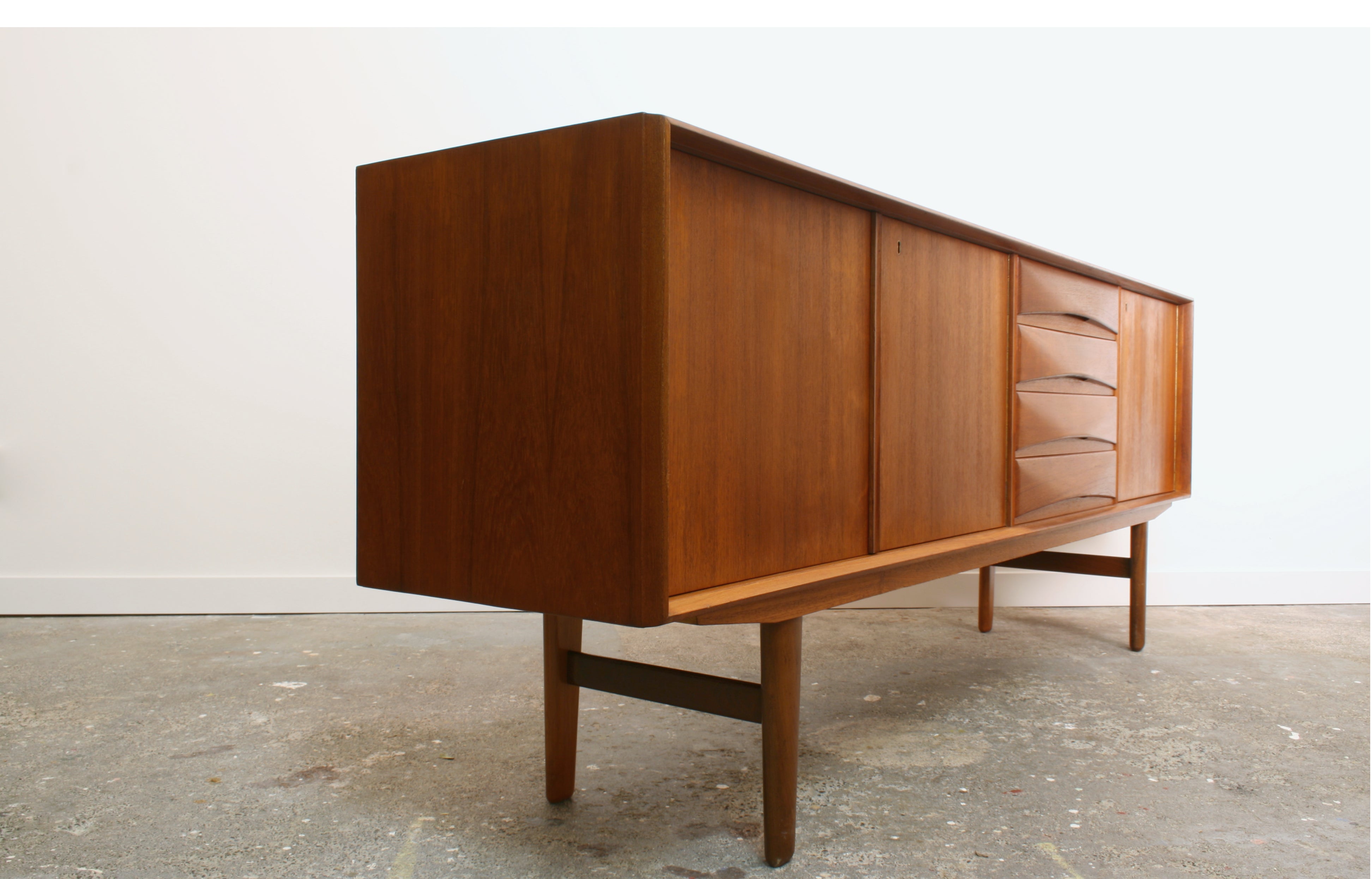 Norwegian teak sideboard with shadows highlighting curved drawer fronts.