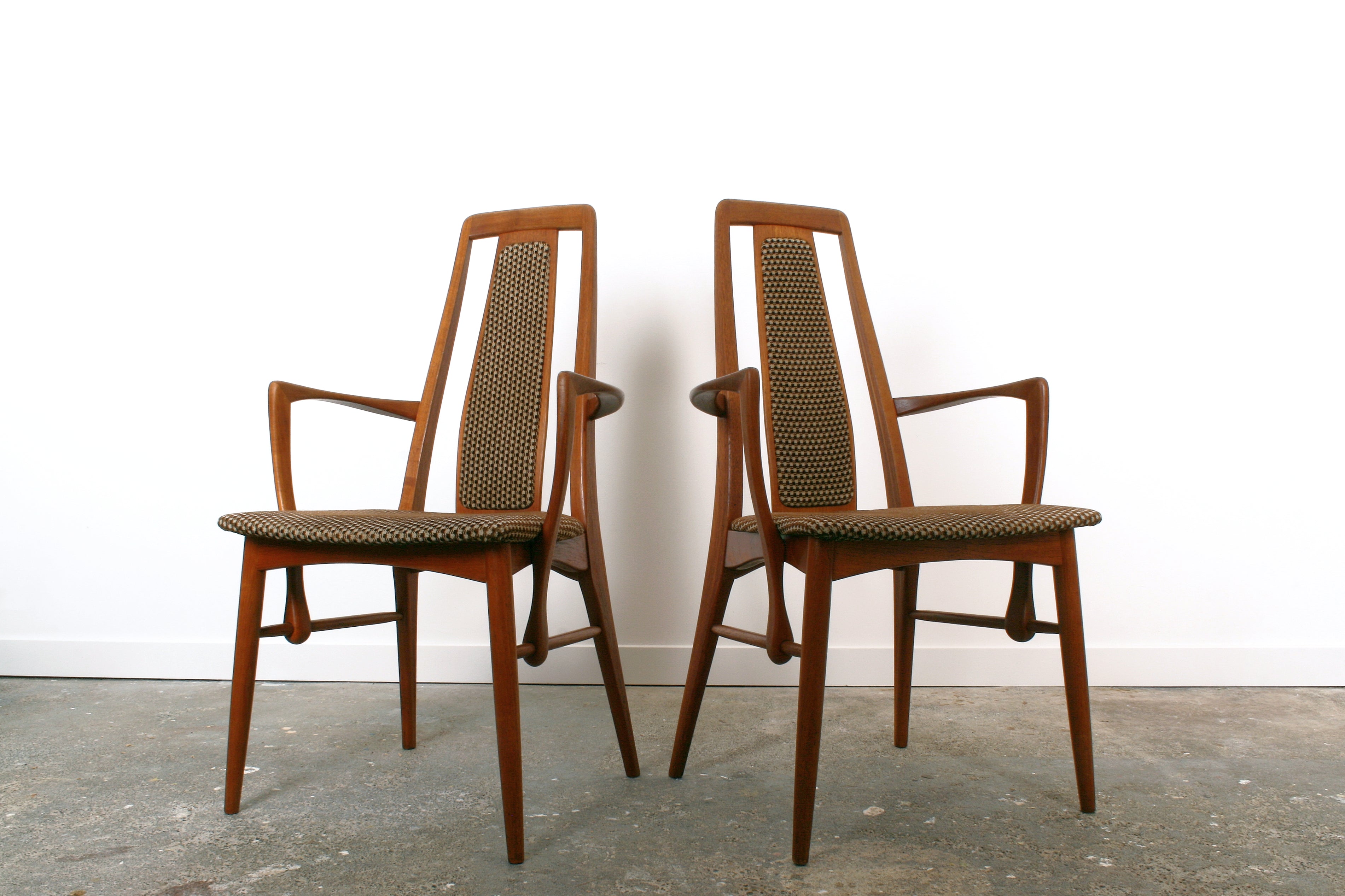 A pair of Danish mid century teak carvers by Koefoeds Hornslet. Distinctive structural arm detail.