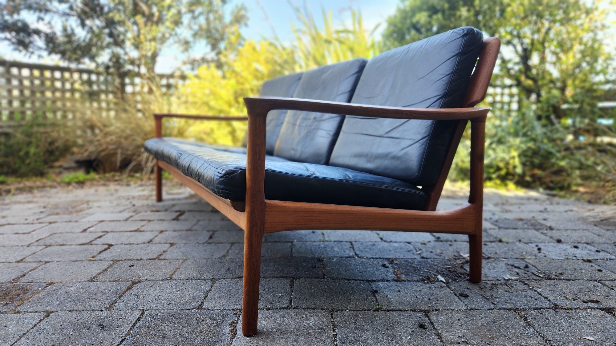 Teak Mid Century sofa by Mann Mobler of West Germany. Seen in stunning profile. with leather cushions.
