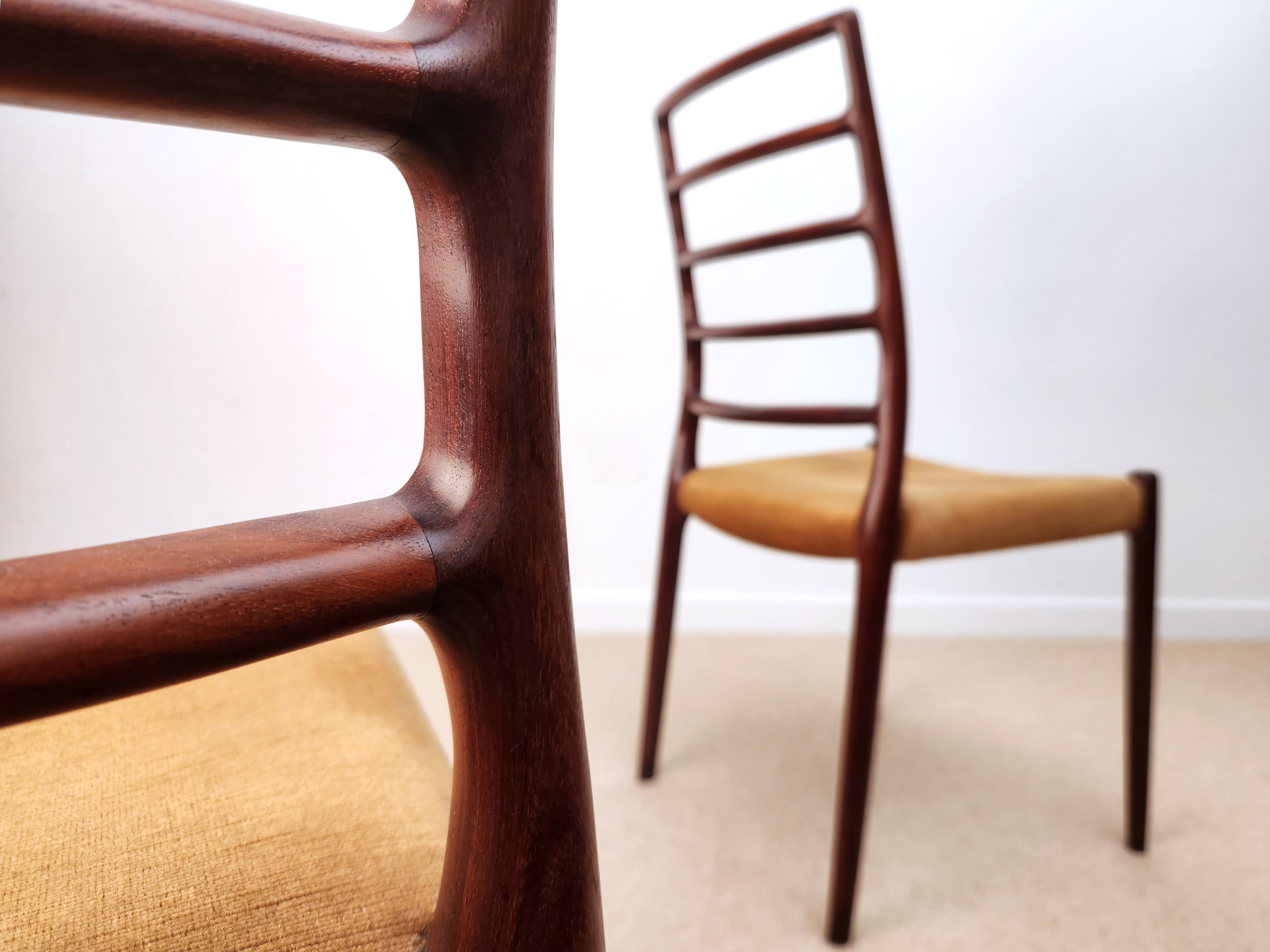Moller Danish chairs -  model 82 with sculpted ladderbacks. One chair in blurred, with closeup joint detail in focus.