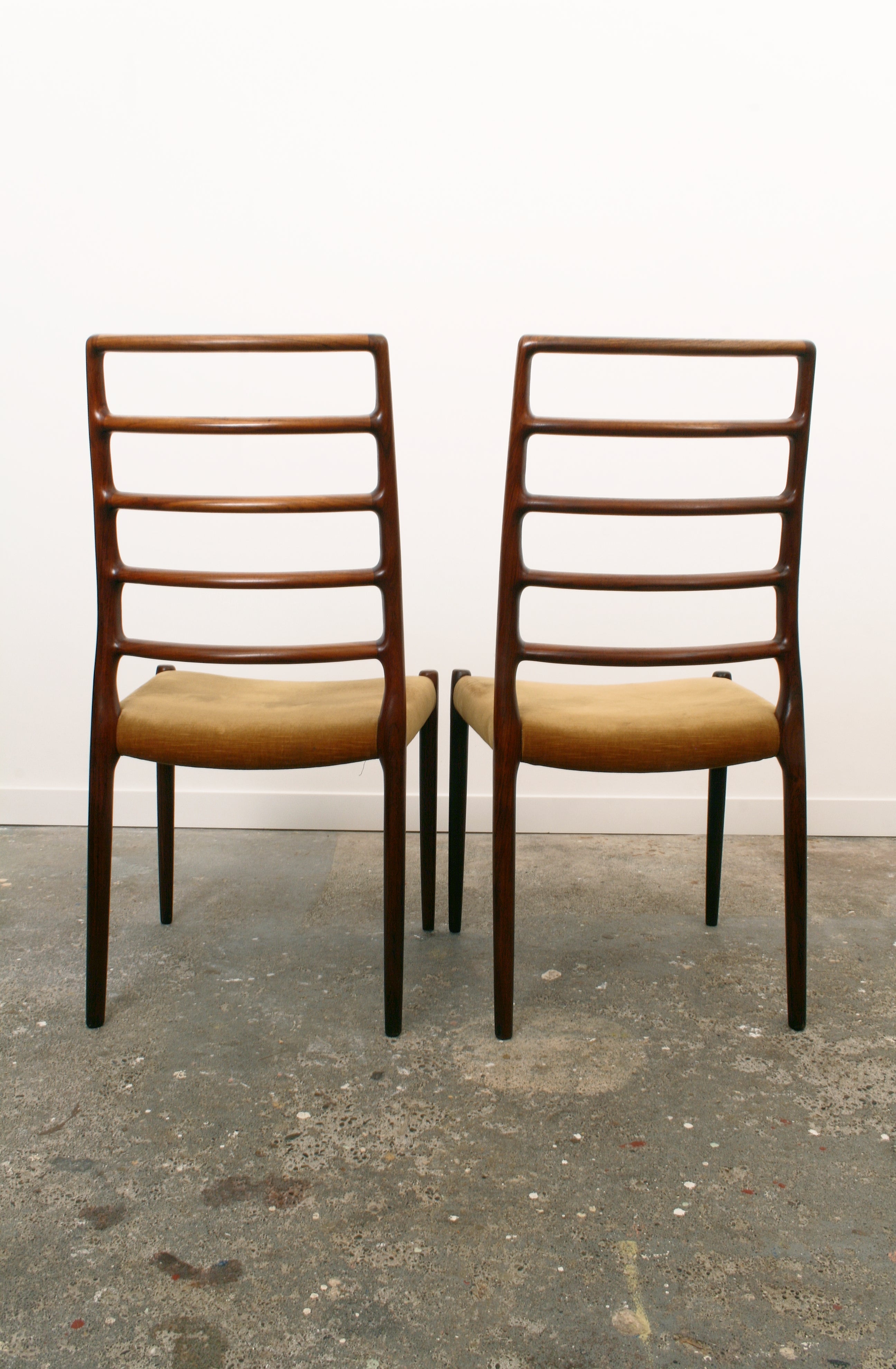Moller Danish chairs pair showing off sculptural backs.